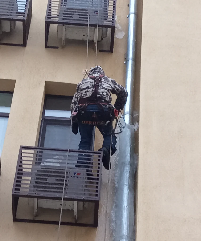 наледь на водосточной трубе и альпинист на верёвках